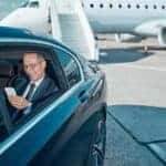Businessman in car at airport near private jet
