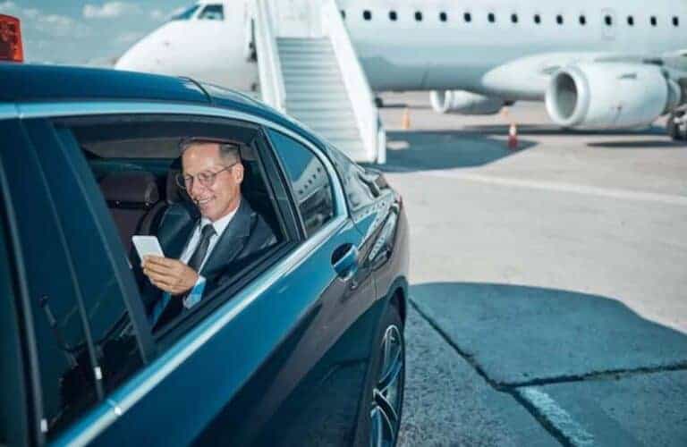 Businessman in car at airport near private jet