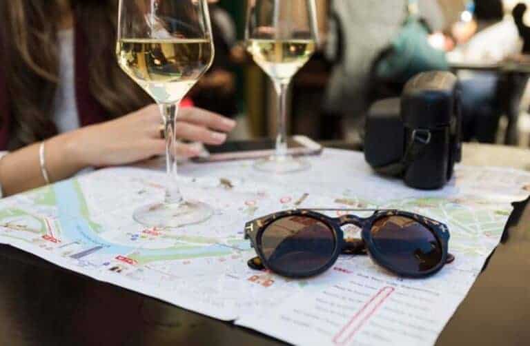 White wine glasses, map, sunglasses on café table