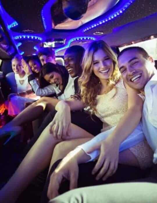 Friends partying inside a neon-lit limousine.