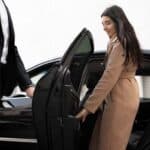 Chauffeur opening car door for woman entering sedan