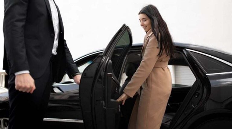 Chauffeur opening car door for woman entering sedan