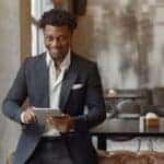 Smiling businessman using tablet in modern cafe