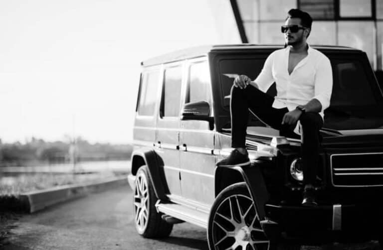 Man sitting on black SUV wearing sunglasses