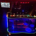 Neon-lit limousine interior with mini bar and screen