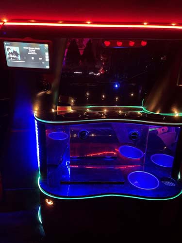 Neon-lit limousine interior with mini bar and screen