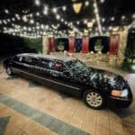 Black stretch limousine under decorative string lights