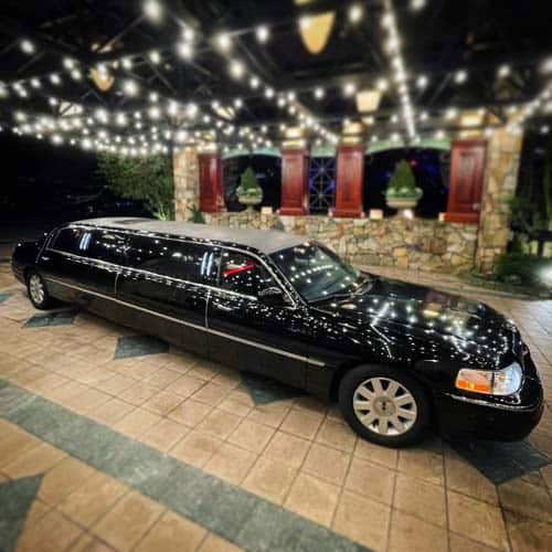 Black stretch limousine under decorative string lights