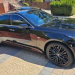 Black luxury sedan parked in residential driveway