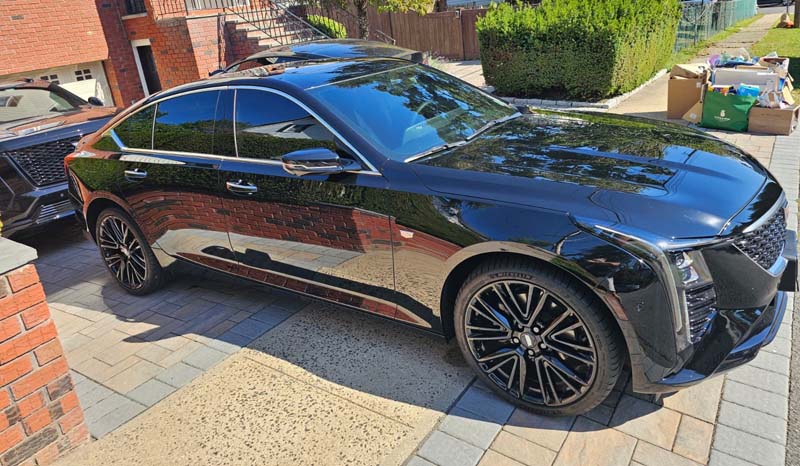 Black luxury sedan parked in residential driveway