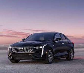 Black luxury sedan parked by ocean at sunset
