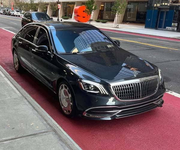 Black luxury sedan parked on city street curb