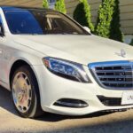 White Mercedes-Benz Maybach luxury sedan on red carpet.