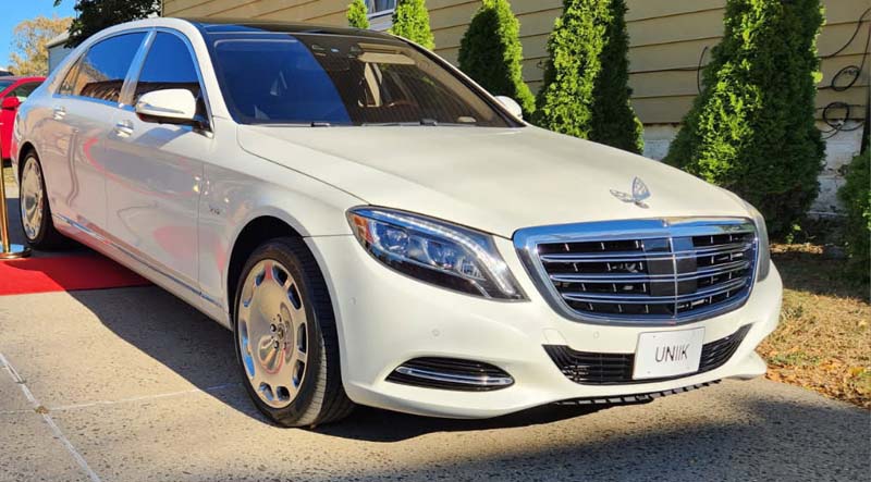 White Mercedes-Benz Maybach luxury sedan on red carpet.