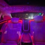 Luxury car interior with purple starlight ceiling and red ambient lighting.