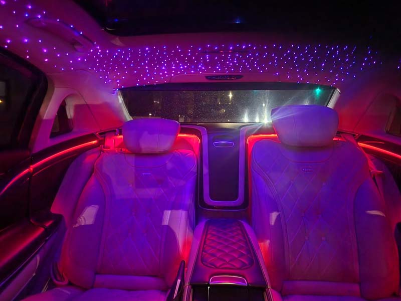 Luxury car interior with purple starlight ceiling and red ambient lighting.