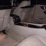 Luxurious car interior with quilted seats and two drinks.