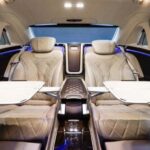 Luxurious car interior with quilted beige seats and deployable tables.