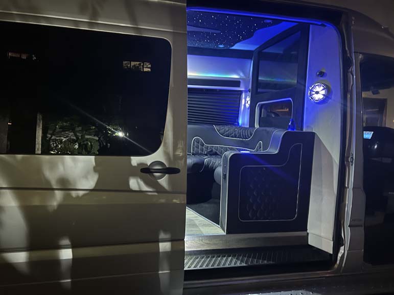 Luxury van interior featuring blue LED lighting and plush seating.