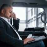Businessman using laptop in backseat of car
