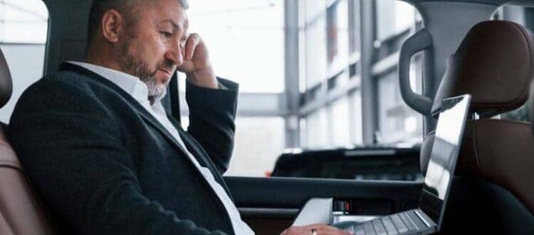 Businessman using laptop in backseat of car