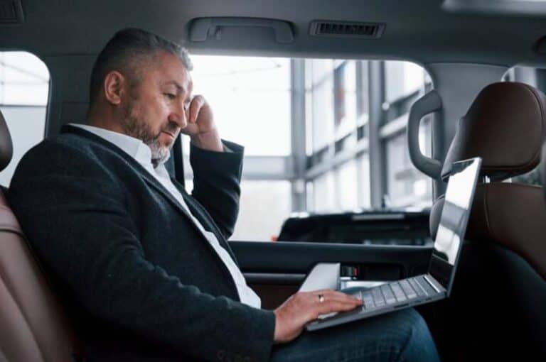 Businessman using laptop in backseat of car