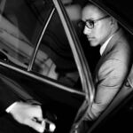 Man in suit sitting inside car, black and white