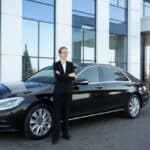 Businesswoman standing beside black luxury sedan outside office building