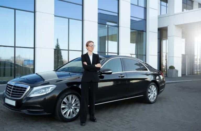 Businesswoman standing beside black luxury sedan outside office building