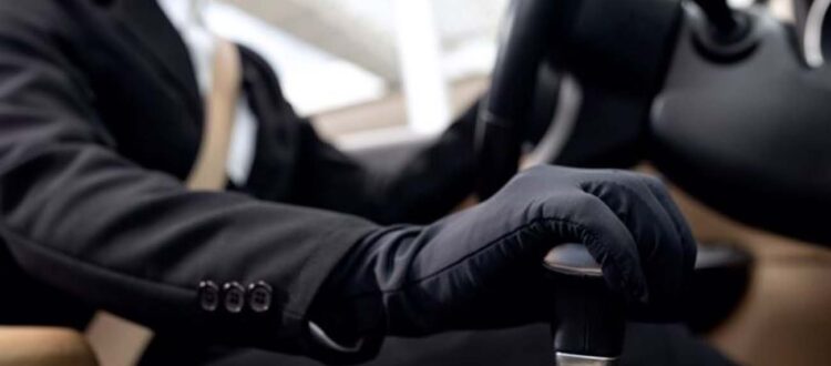 Man in suit driving car wearing black gloves