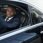 Man in suit exiting luxury car with driver