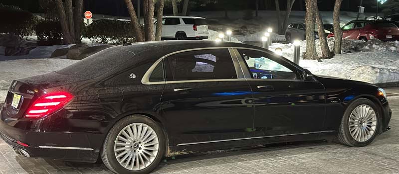 Black luxury sedan parked at night in snow