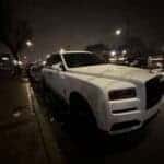 White Rolls-Royce SUV parked on city street at night
