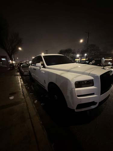 White Rolls-Royce SUV parked on city street at night