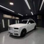 White Rolls-Royce SUV in modern dark garage