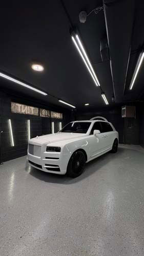 White Rolls-Royce SUV in modern dark garage