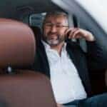 Smiling businessman sitting in back seat of car