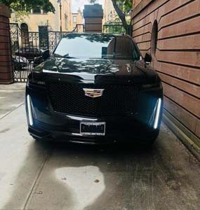 Black Cadillac SUV parked in narrow driveway