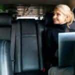 Woman using laptop in backseat of car