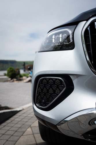 Close-up of white car headlight and front grille