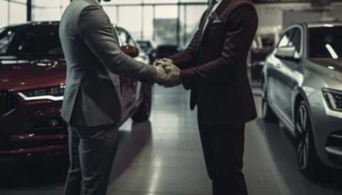 Two men shaking hands in car dealership showroom