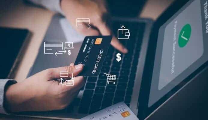 Person holding credit card shopping online on laptop