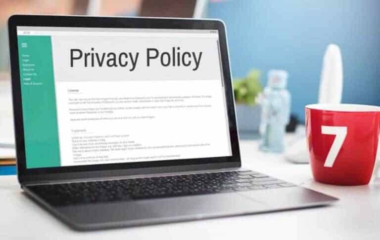 Laptop displaying privacy policy beside red mug.