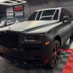 Matte black Rolls-Royce SUV in detailing shop