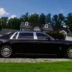 Black luxury sedan parked in front of suburban house