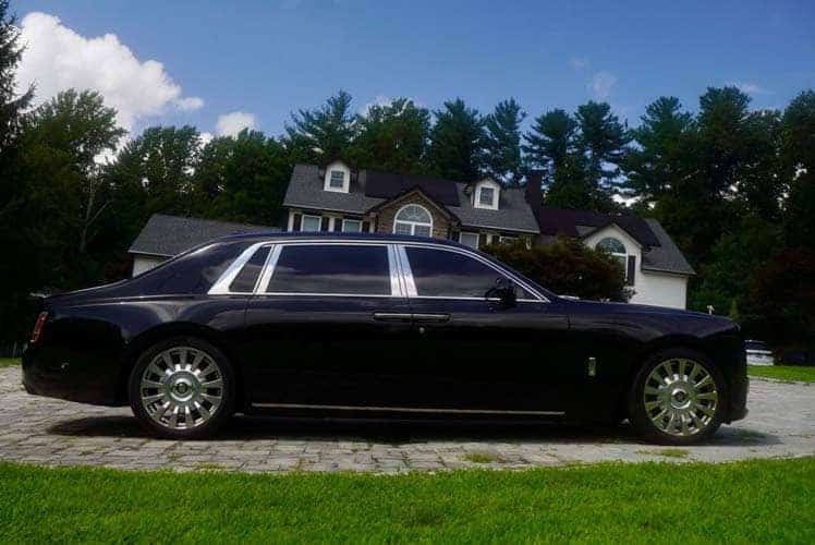 Black luxury sedan parked in front of suburban house