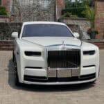 White Rolls-Royce parked in front of brick gate