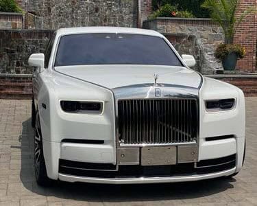 White Rolls-Royce parked in front of brick gate