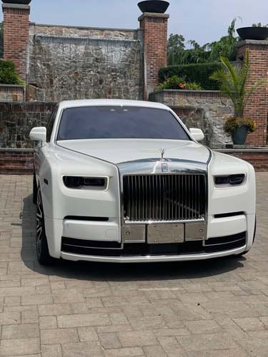 White Rolls-Royce parked in front of brick gate