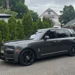 Gray Rolls-Royce SUV parked on suburban street